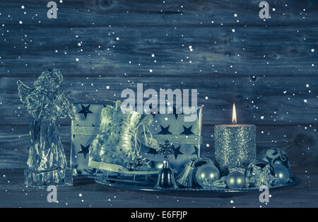 Blu scuro decorazione di Natale con candela e presenta sullo sfondo di legno con un angelo di vetro. Foto Stock