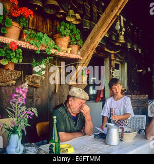 Stanco anziani agricoltori di montagna con il nipote di fronte al loro chalet Savoia sulle Alpi francesi Francia Foto Stock