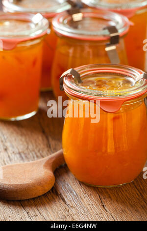 In casa il melone marmellata in un barattolo di conservazione con un cucchiaio di legno sul vecchio tavolo in legno Foto Stock