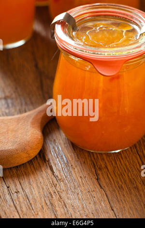 In casa il melone marmellata in un barattolo di conservazione con un cucchiaio di legno sul vecchio tavolo in legno Foto Stock