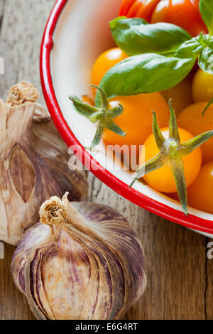 Appena raccolto i pomodori in una ciotola di smalto carne e bulbi di aglio Foto Stock