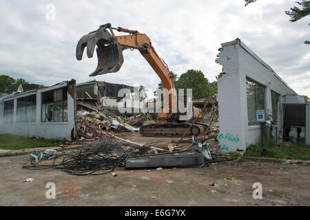 Escavatore con benna mordente facendo lavori di demolizione su edificio per uffici a Norwalk, CT. Materiali ordinati per il riciclaggio. Foto Stock