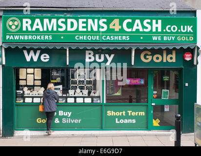 Donna che guarda nella finestra del Ramsdens 4 cash shop, Chester-le-Street, North East England, Regno Unito Foto Stock