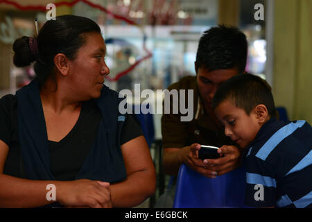 San Pedro Sula, Cortez, Honduras. 28 Luglio, 2014. Sandra Herrera orologi suo figlio Alex, 17, centro, momenti dopo si arriva a San Pedro Sula dopo essere stato espulso dal Messico il suo modo per gli Stati Uniti Il fratello John Terry, guarda a. Sotto pressione da parte degli Stati Uniti, le autorità messicane stanno intensificando gli sforzi per intercettare i bambini migranti in direzione nord. © Miguel Juarez Lugo/ZUMA filo/Alamy Live News Foto Stock