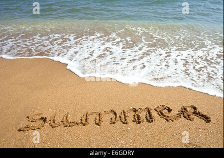 'Summer' ; scritta nella sabbia sulla spiaggia con onde azzurre in background Foto Stock