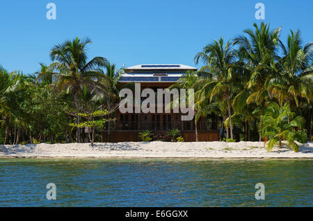 Off-grid beach house con pannelli solari sul tetto e vegetazione tropicale su una delle isole del Mar dei Caraibi, Panama Foto Stock