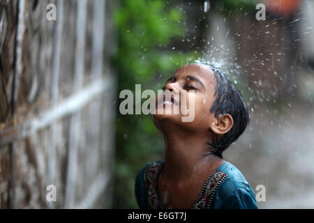 Dacca in Bangladesh. 23 Ago, 2014. Baraccopoli bambini godendo la pioggia a Dhaka. Dacca è la seconda più vulnerabili alla città di gravi inondazioni tra nove città costiere globalmente e rimarrà tale fino al 2100 a meno che le misure volte a contrastare la minaccia sono presi, uno studio internazionale suggerisce. © Zakir Hossain Chowdhury/ZUMA filo/Alamy Live News Foto Stock