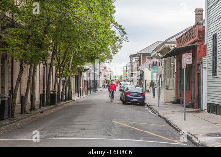 Uomo Bicicletta Equitazione verso il basso di una strada a senso unico nel Quartiere Francese di New Orleans, Louisiana Foto Stock