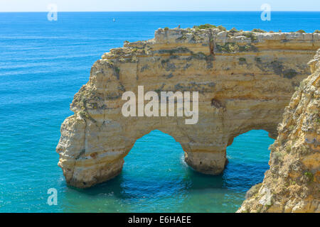 Tourist seduto sulla cima di un arco di mare in Algarve, PORTOGALLO Foto Stock