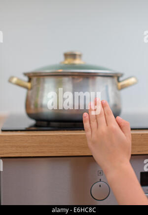 Bambino tocca padella calda sul fornello. Situazione di pericolo a casa. Foto Stock