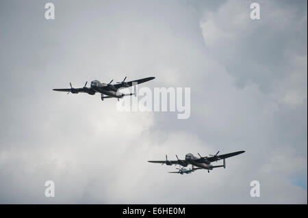 Aerodromo di Dunsfold, SURREY REGNO UNITO. Sabato 23 agosto 2014. Due bombardieri Lancaster visualizza al decimo Dunsfold ali e le ruote. La RAF Battle of Britain Memorial Flight bomber è unita dalla Canadian Warplane Heritage Museum Lancaster VRA, il solo altro Lanc navigabilità nel mondo. Uno Spitfire può essere visto dietro la parte posteriore di Lancaster. Credito: Malcolm Park editoriale/Alamy Live News. Foto Stock