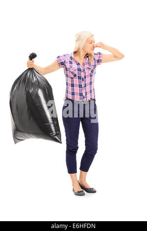 A piena lunghezza Ritratto di una donna tenendo un puzzolente garbage bag Foto Stock