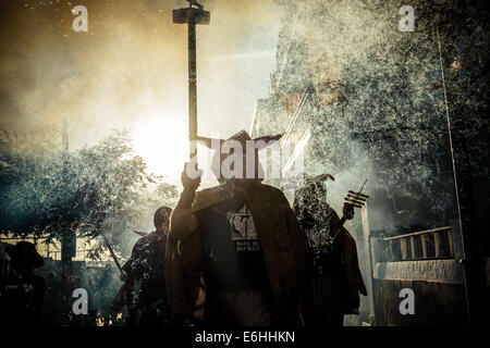 Sitges, Spagna. 23 Ago, 2014. Un membro di "Ball de Diables' mette fuori i suoi fuochi d'artificio al tramonto durante la " Festa Major de Sitges' © Matthias Oesterle/ZUMA filo/ZUMAPRESS.com/Alamy Live News Foto Stock