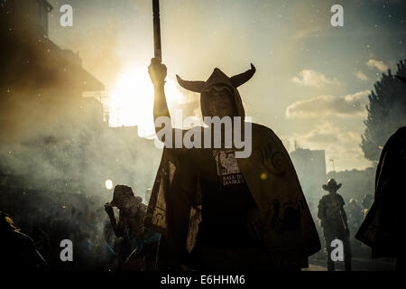 Sitges, Spagna. 23 Ago, 2014. Un membro di "Ball de Diables' mette fuori i suoi fuochi d'artificio al tramonto durante la " Festa Major de Sitges' © Matthias Oesterle/ZUMA filo/ZUMAPRESS.com/Alamy Live News Foto Stock