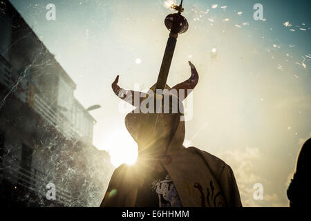 Sitges, Spagna. 23 Ago, 2014. Un membro di "Ball de Diables' mette fuori i suoi fuochi d'artificio al tramonto durante la " Festa Major de Sitges' © Matthias Oesterle/ZUMA filo/ZUMAPRESS.com/Alamy Live News Foto Stock