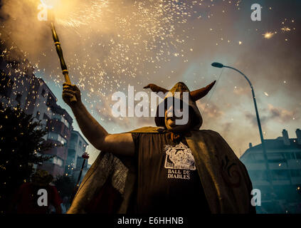 Sitges, Spagna. 23 Ago, 2014. Un membro di "Ball de Diables' mette fuori i suoi fuochi d'artificio al tramonto durante la " Festa Major de Sitges' © Matthias Oesterle/ZUMA filo/ZUMAPRESS.com/Alamy Live News Foto Stock