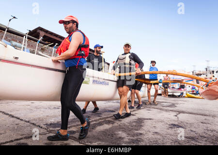 Sei uomo squadra di canottaggio lanciando una canoa outrigger at Playa San Juan, Tenerife, Isole Canarie, Spagna. Foto Stock