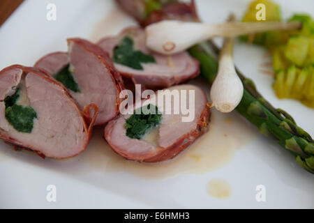 Filetto alla griglia di carne di maiale con ripieno di formaggio e spinaci rivestita con pancetta. Piatto di lato grigliate di giovani cipolla, gli asparagi e le zucchine. Foto Stock