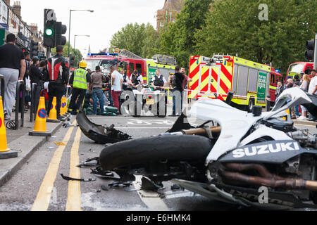 Londra, Regno Unito. 24 Agosto, 2014. Paramedici e vigili del fuoco di occuparsi di un ferito biker che sembrava avere eseguito nel retro di un auto in corrispondenza dell'intersezione di Chamberlayne Road e Harvist strada in Kensal Green. Un certo numero di motociclisti era stato ruggente su e giù per la strada come primo giorno del carnevale di Notting Hill è venuto a una stretta. Credito: Paolo Davey/Alamy Live News Foto Stock