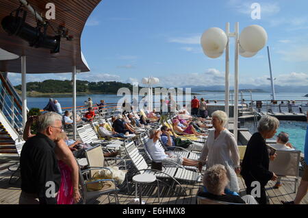 La barca continua lungo la costa norvegese, proseguendo costantemente verso sud, passando per le piccole isole. Mentre sul ponte le persone continuano Foto Stock