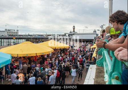 Brighton, Regno Unito. 24 Ago, 2014. Holiday Maker guarda dalla memoria PROM come Francois Monin, assistente bar manager al Lucky Voice, Brighton, imposta un mondo nuovo record di velocità per l'apertura 2000 bottiglie di birra. Egli ha infranto la corrente Guinness World Record che sorgeva a 28 minuti 11secondi da quasi 4 minuti, apertura 2030 bottiglie in 24 minuti 37 secondi. La manifestazione si è svolta a Azure bar e ristorante sulla spiaggia di Brighton tra Brighton Pier e Brighton ruota ed è stato sponsorizzato da Asahi Beer. Credito: Julia Claxton/Alamy Live News Foto Stock