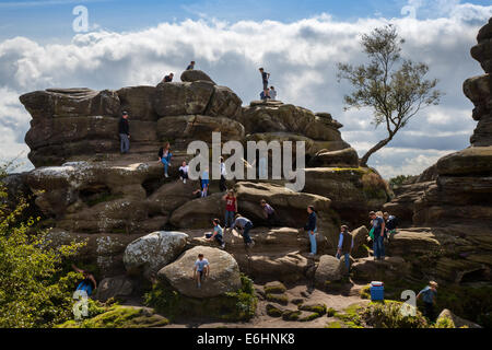 Persone che si arrampicano e si arrampicano sulle Brimham Rocks; Brimham Crags è una collezione di formazioni rocciose naturali equilibrate scolpite nel corso dei secoli da ghiaccio, vento e pioggia nelle North Yorkshire Dales. Vacanze di bambini attivi e turisti in visita presso il National Trust Site, un'ottima giornata per le famiglie e gli scalatori, godendo di una particolare serie di formazioni rocciose composte da graniglia di macina modellata dal vento e dal tempo Foto Stock