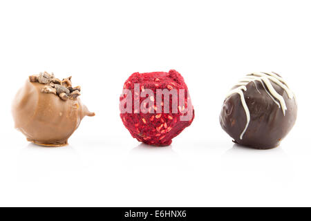 Praline di cioccolato con mandorle, miele, grappa liquore e lampone polvere isolata su sfondo bianco Foto Stock