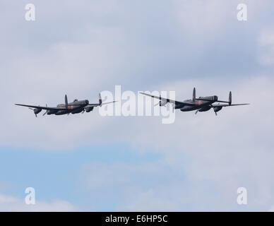 Dunsfold, UK. 23 Ago, 2014. La Canadian Warplane Heritage Museum Avro Lancaster Mk. X Guerra Mondiale 2 bombardiere pesante è nel Regno Unito per un mese e fornisce la possibilità di vedere e il Battle of Britain Memorial Flight Avro Lancasterflying insieme nel Regno Unito. Il canadese del piano è dedicato alla memoria di P/0 Andrew Mynarski VC sono entrambi visto qui volare in formazione a Dunsfold sabato 23 agosto Credito: Niall Ferguson/Alamy Live News Foto Stock