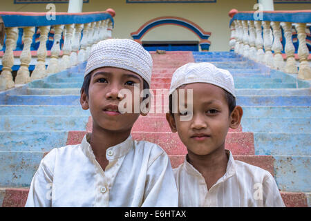 Due i giovani cambogiani Cham ragazzi musulmani, indossa gli abiti migliori, seduti sulle scale di una moschea di Kompong Cham, Cambogia. Foto Stock