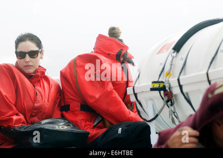 Due donne miserabile tentativo di nascondere da congelamento a spruzzo a freddo su un avvistamento di balene Giro in barca sulla St Lawrence Foto Stock