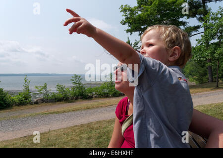 A due anni qualcosa di puntamento fuori alla sua mamma, con la St Lawrence river a Québec al di là Foto Stock