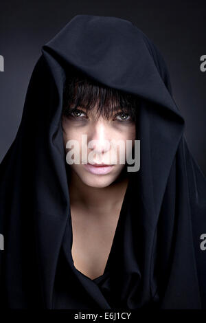 Scary donna con un viso pallido. Coperto con un panno nero. Foto Stock