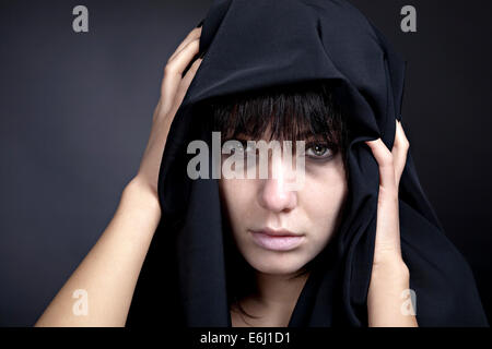 Scary donna con un viso pallido. Coperto con un panno nero. Foto Stock