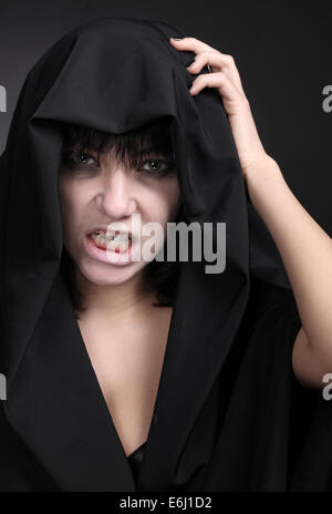 Scary donna con un viso pallido. Coperto con un panno nero. Foto Stock