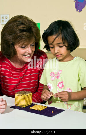 5-6 anni anni etnica diversità razziale razziale multiculturale multi culturale tra insegnanti Montessori lavorando insieme ragazza conteggio Foto Stock