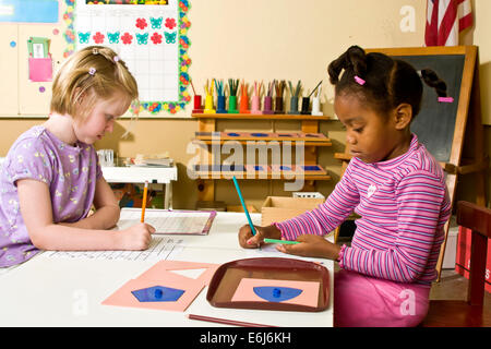 Multi etnico diversità razziale razziale diverse interracial due 5-6 anni anni ragazza bianco nero ragazza scrive opera lavorando insieme la scrivania. Il sig. © Myrleen Pearson Foto Stock