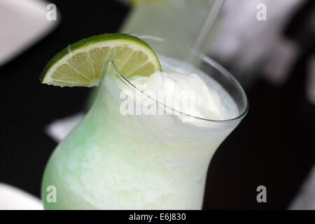 Vetro con una limonata ghiacciata drink servito con una piccola fetta di limone. Foto Stock