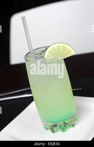 Vetro con una limonata ghiacciata drink servito con una piccola fetta di limone. Foto Stock