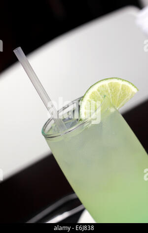 Vetro con una limonata ghiacciata drink servito con una piccola fetta di limone. Foto Stock