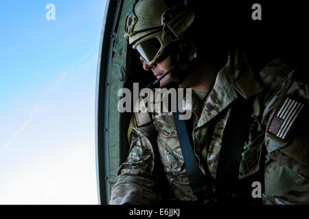 US Air Force Tech. Sgt. Justin McCaffrey orologi per simulare possibili minacce nemiche dalla porta aperta di un elicottero durante il funzionamento la bandiera verde Little Rock esercizio luglio 30, 2014 a Fort Polk, Louisiana. Foto Stock