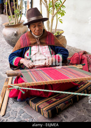 Il quechua donna indiana si intreccia con una fascetta telaio all'interno dell'Arte Precolombiana Museum - Cuzco, Perù Foto Stock