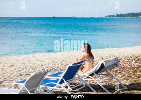 Un tatuato Caucasian donna in un bikini gode del mare dei Caraibi sulla spiaggia di St. Croix, U.S. Isole Vergini. Foto Stock