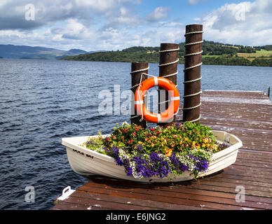 Display floreale in una piccola barca su un molo al Baia d'anatra, Loch Lomond,Scozia. Foto Stock