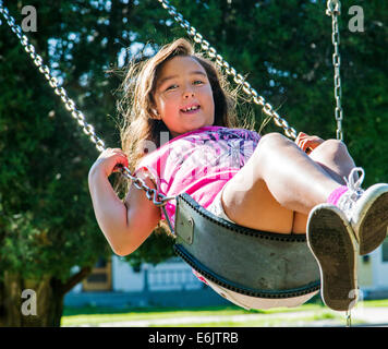 Estate fotografia di sette anno vecchia ragazza su un parco giochi swing Foto Stock
