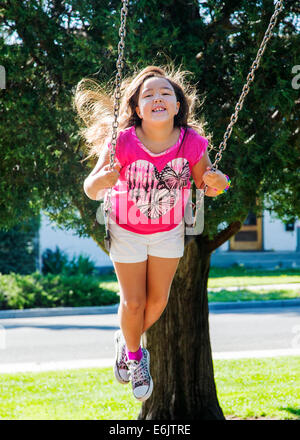 Estate fotografia di sette anno vecchia ragazza su un parco giochi swing Foto Stock