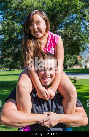 Padre tenendo la sua figlia di sette anni sulle spalle Foto Stock