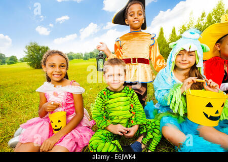 Dei bambini felici in costumi di Halloween di sedersi sull'erba Foto Stock