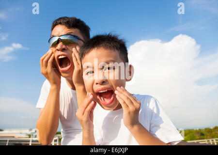 Padre e figlio facendo una grimace insieme nel parco Foto Stock