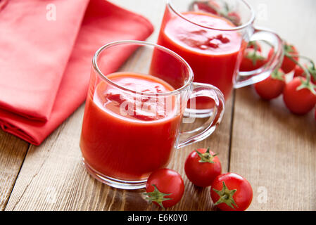 I succhi di pomodoro, bicchieri con pomodori ciliegia sulla tavola di legno Foto Stock