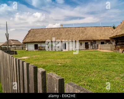 Stile vecchio cascinale polacco con annessi con tetto in paglia e Picket Fence shot contro il cielo blu Foto Stock